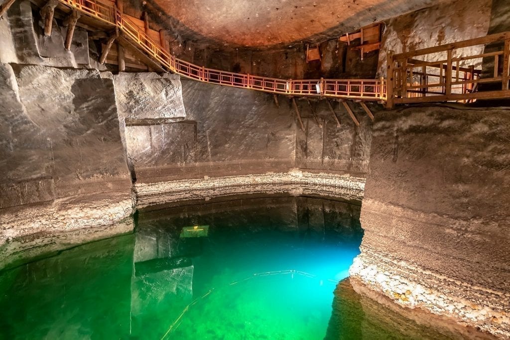 Underground lake in Wieliczka Salt Mine with wooden walking ramps around the edge. Don't miss this incredible place during your 2 day Krakow itinerary!