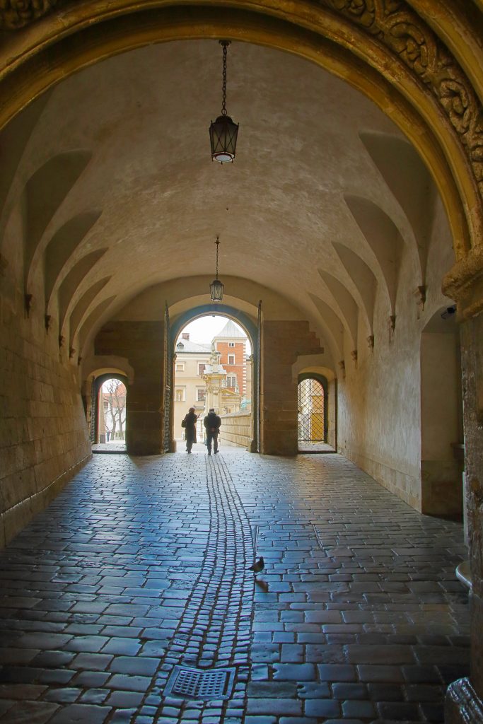 photo of cobblestone path covered by an arch in wawel castle poland 