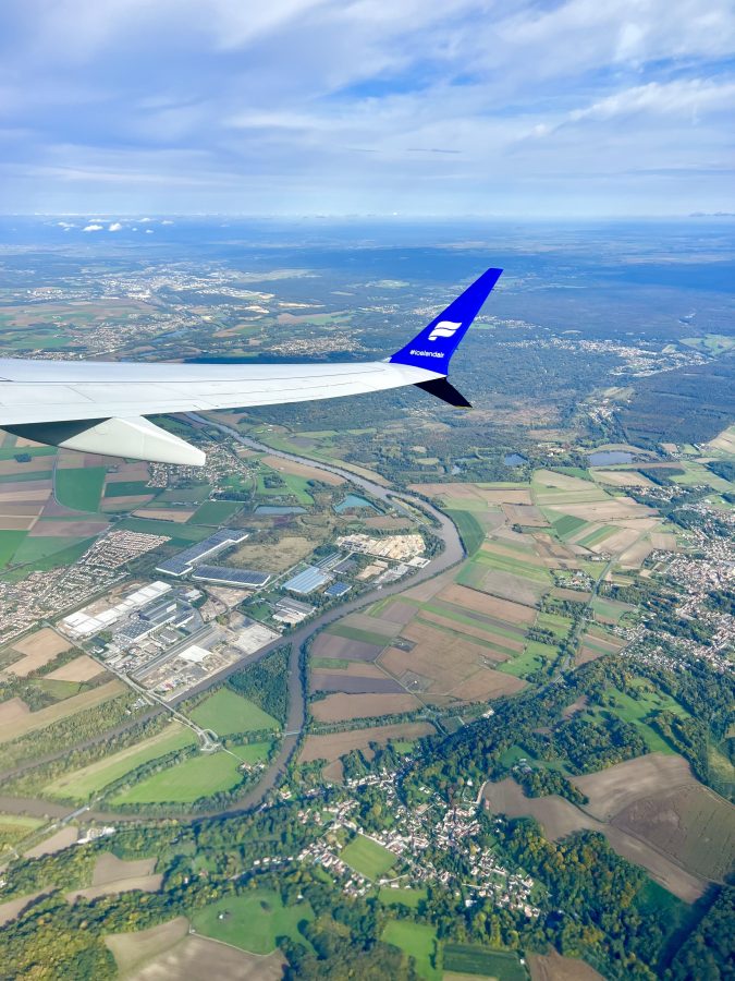 plane wing in the foreground of the photo with french countryside visible below