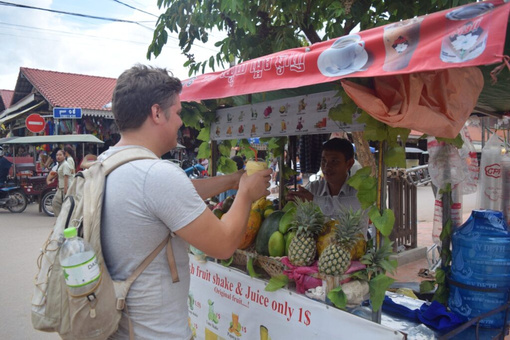 jeremy storm purchasing fruit juice from a street stall in siem reap cambodia