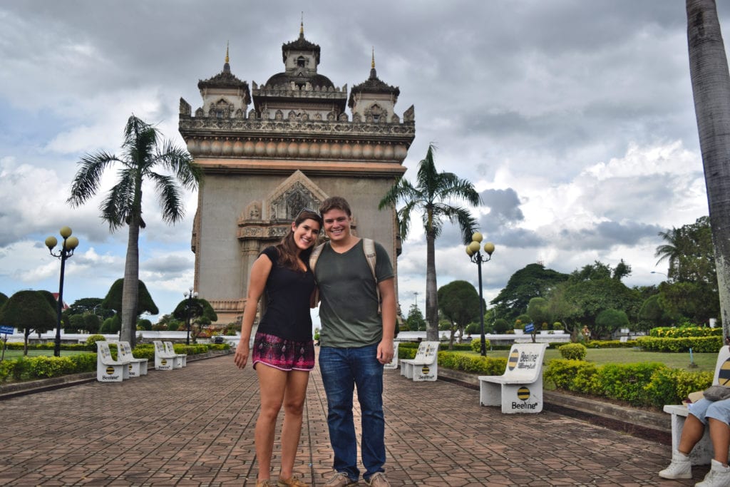 kate storm and jeremy storm standing in front of laos victory gate