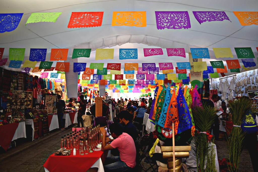 inside of a souvenir market with colorful flags handing from the ceiling as seen visiting oaxaca city mexico