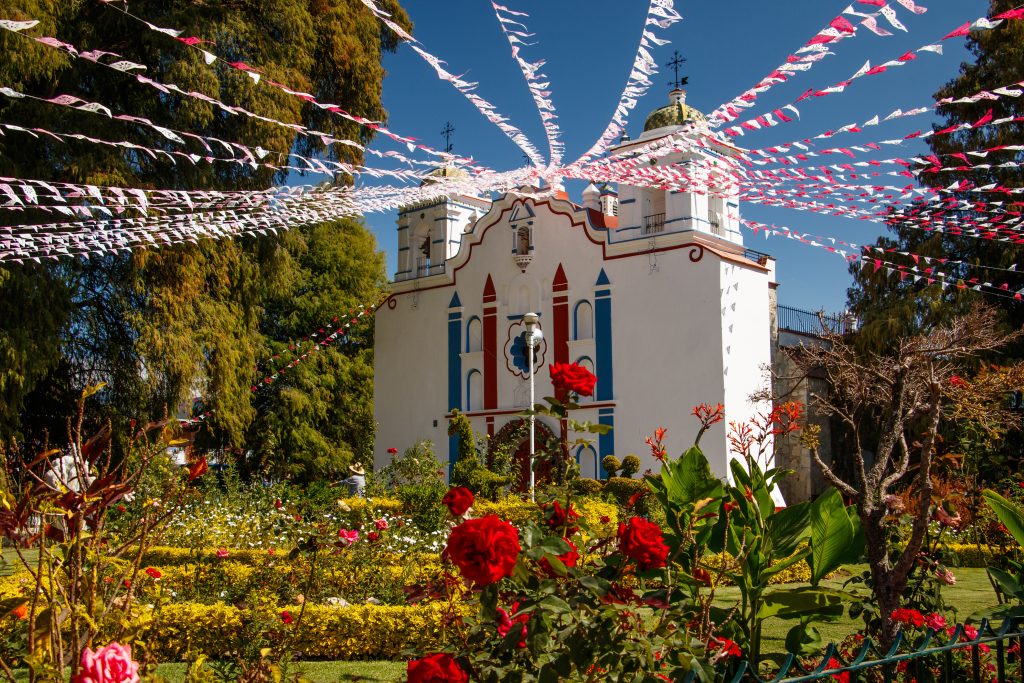 colorful church in the region of oaxaca mexico with flags dangling from it
