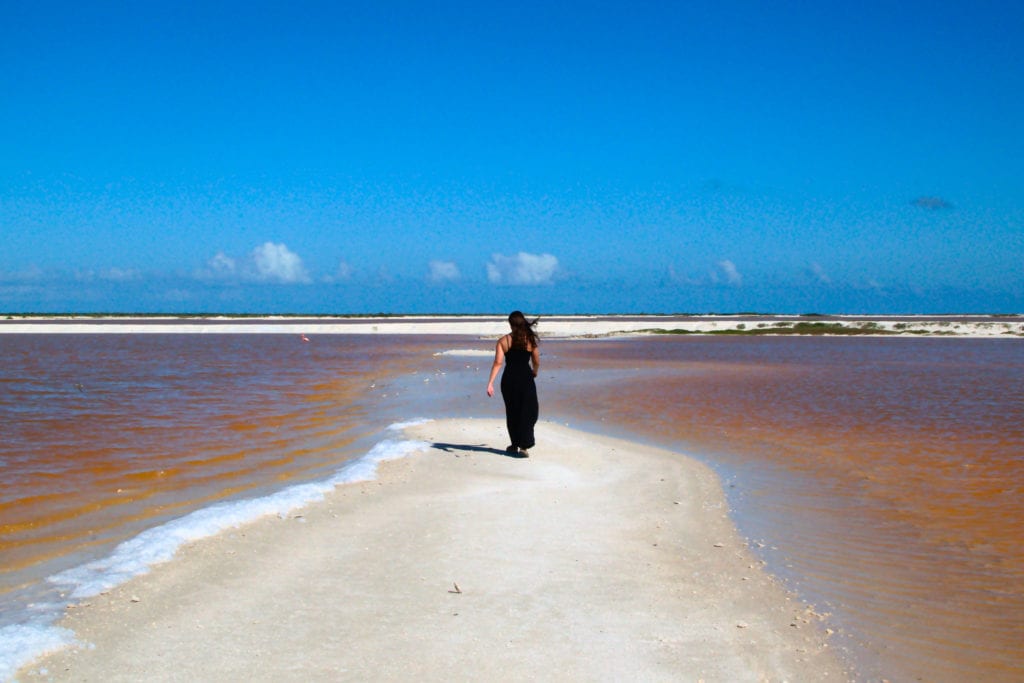 Kate Storm walking away from the camera surrounded by orange lakes on either side