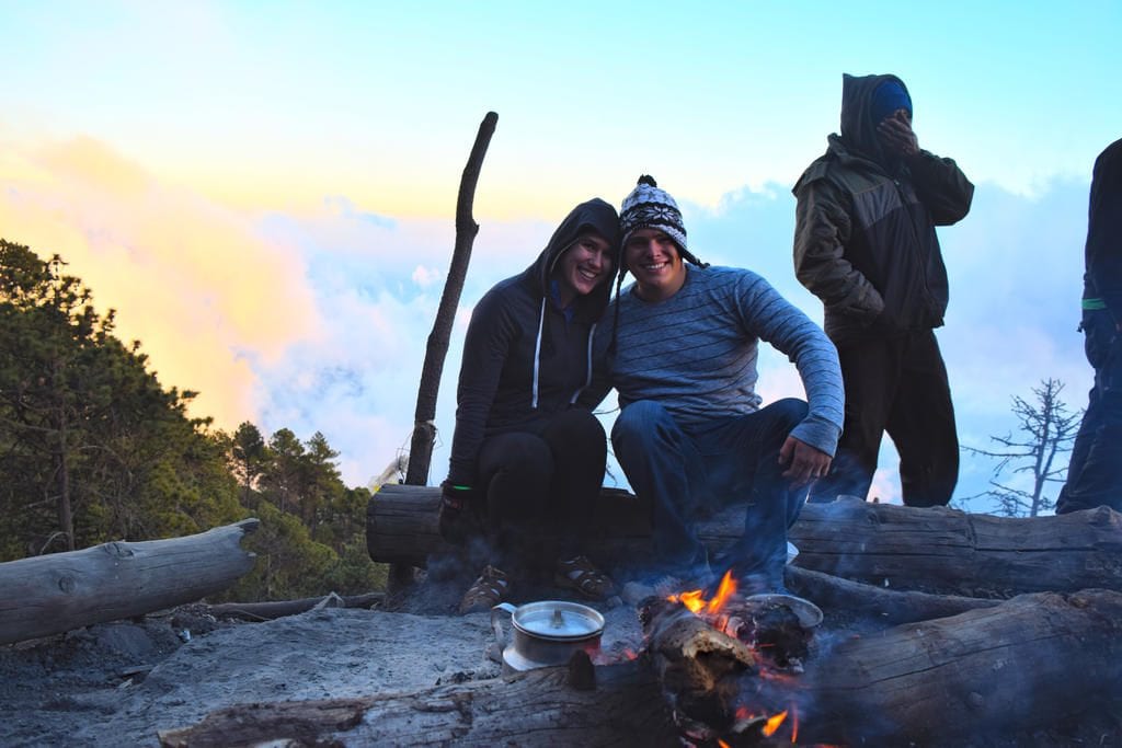 kate storm and jeremy storm sitting at campfire after Hiking Volcano Acatenango