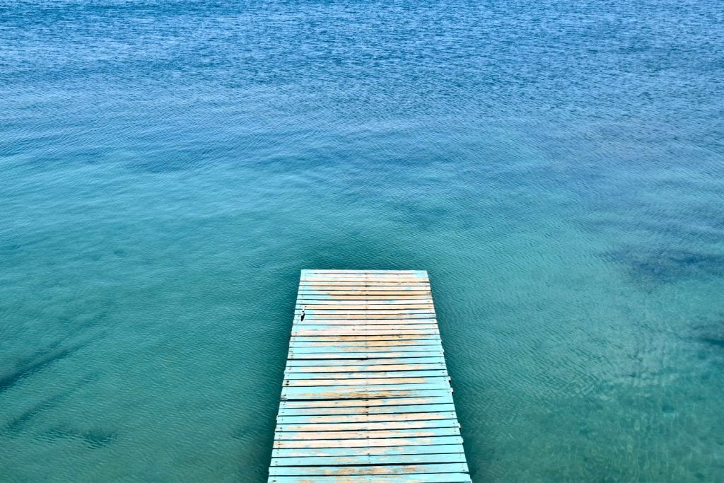 view of a dock over the water in utila honduras as seen from above. views like this don't add to the bottom line of a trip to honduras budget