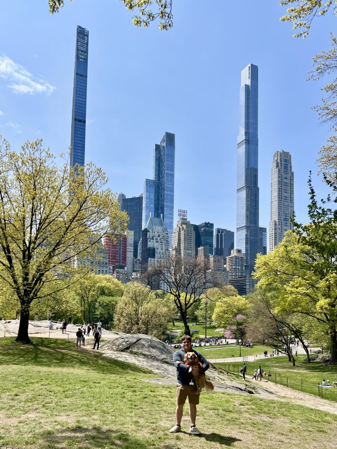 jeremy storm holding his yellow dog ranger in southeast central park new york city with skyscrapers visible behind him