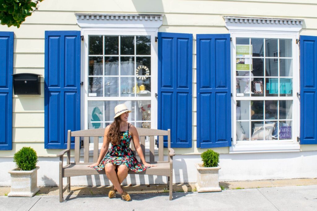 Fun Things to Do in Beaufort NC: Girl on bench in front of boutique with blue shutters