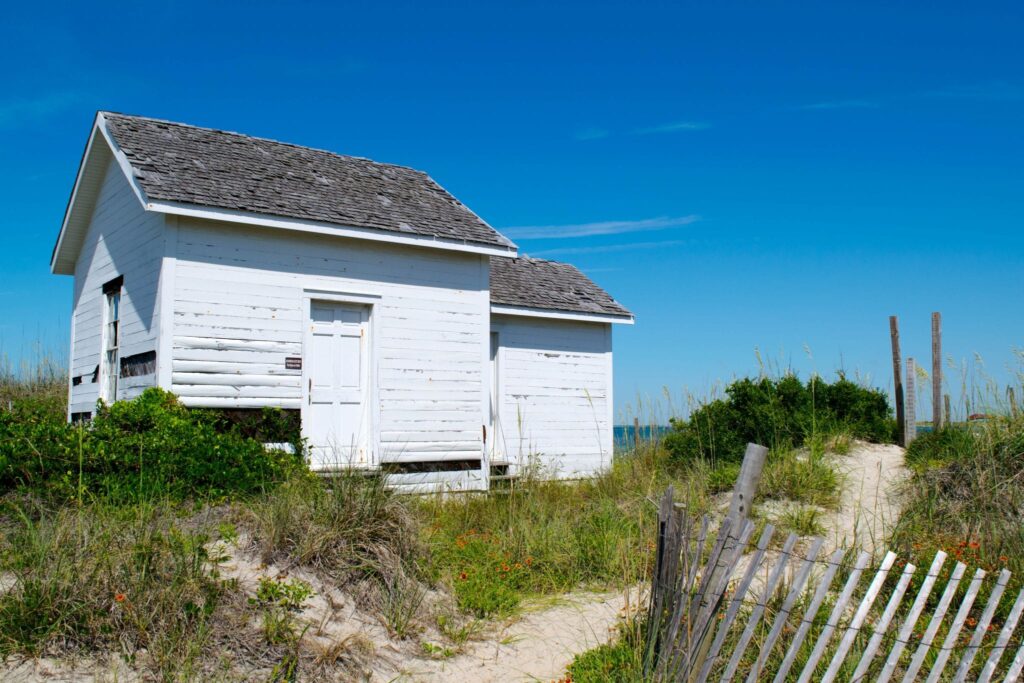Small white outbuilding surrounded by sand dunes on Cape Lookout National Seashore