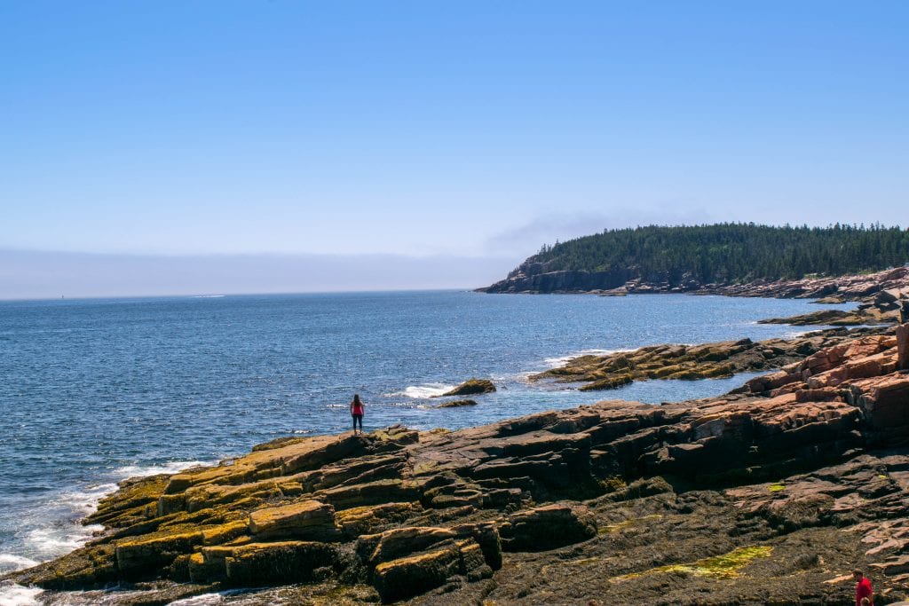 kate storm on the edge of a rocky coastline when visiting acadia national park maine