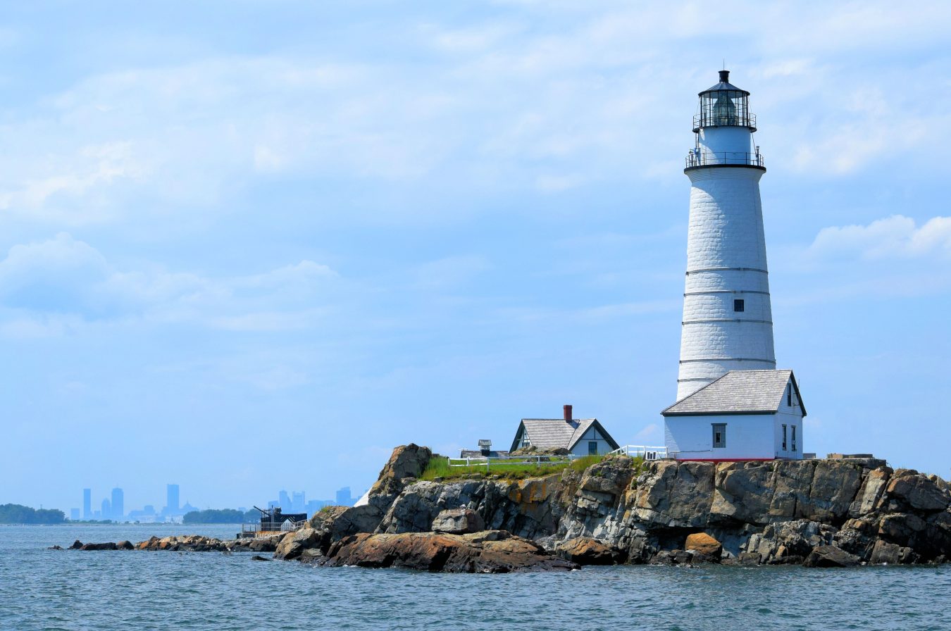 white lighthouse on rocky little brewster island as seen from the water in boston harbor