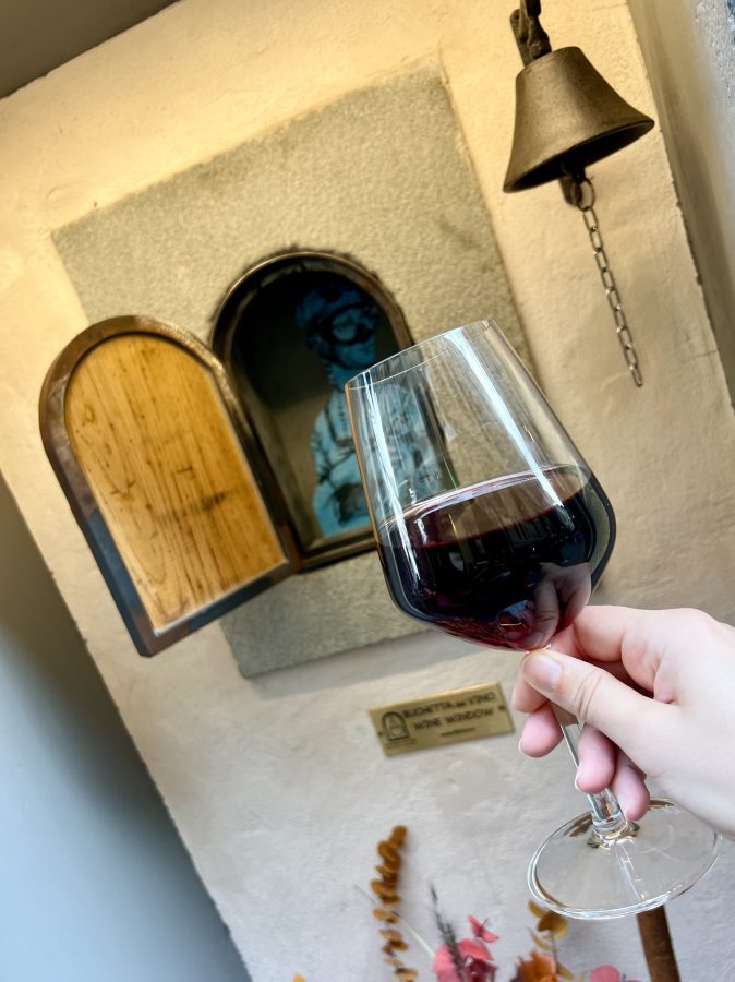 glass of wine being held up in front of an open wine window in florence italy