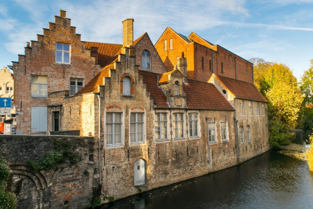 brick buildings along a small canal in bruges. canals are a popular reason to visit both ghent and bruges