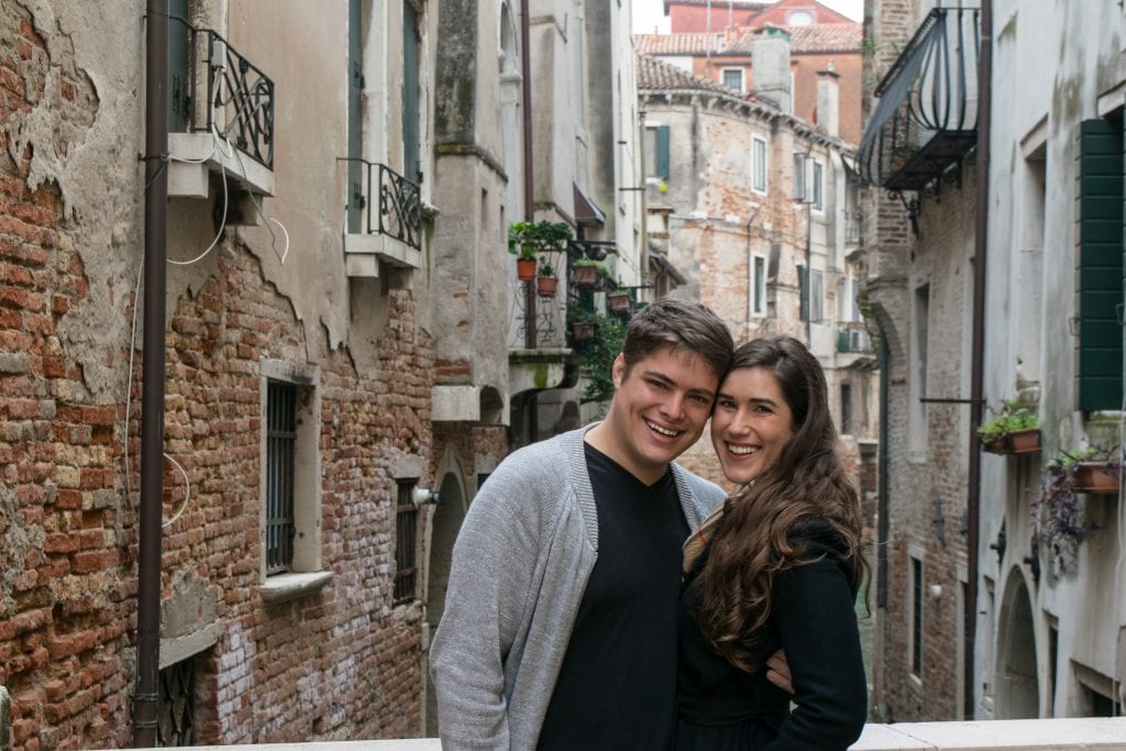 kate storm and jeremy storm posing for a photo in front of a canal during one day in venice italy