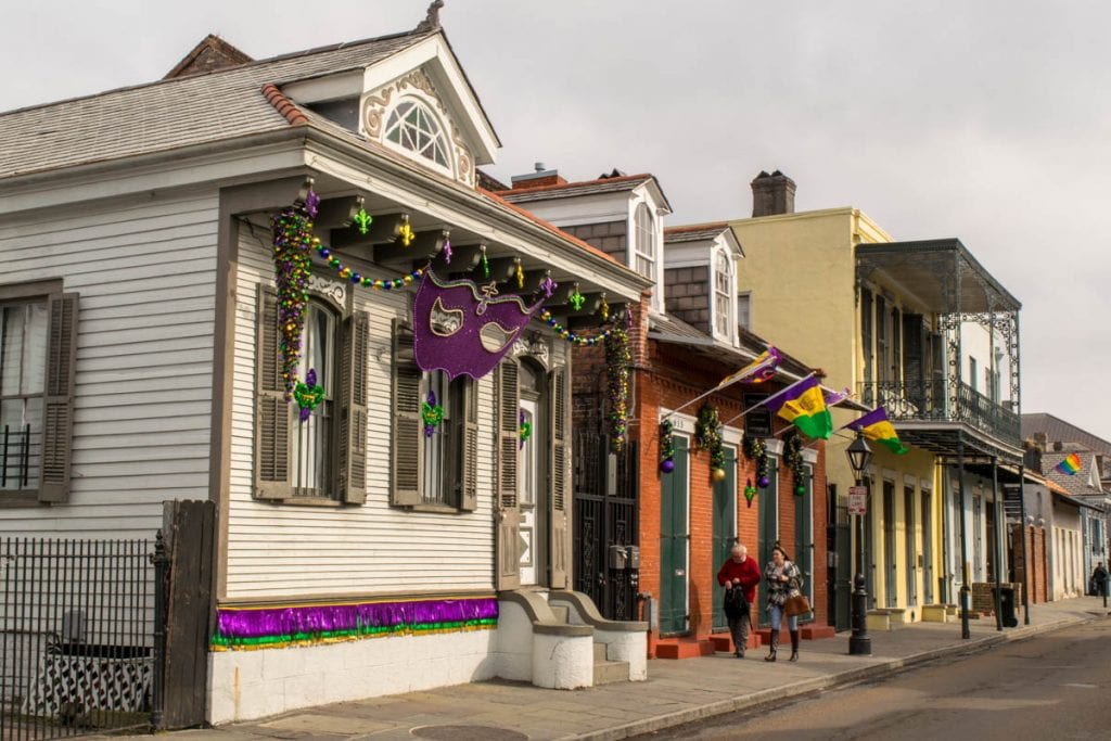 Row of colorful houses in New Orleans French Quarter with Mardi Gras decorations out front, as seen during a long weekend in New Orleans vacation.