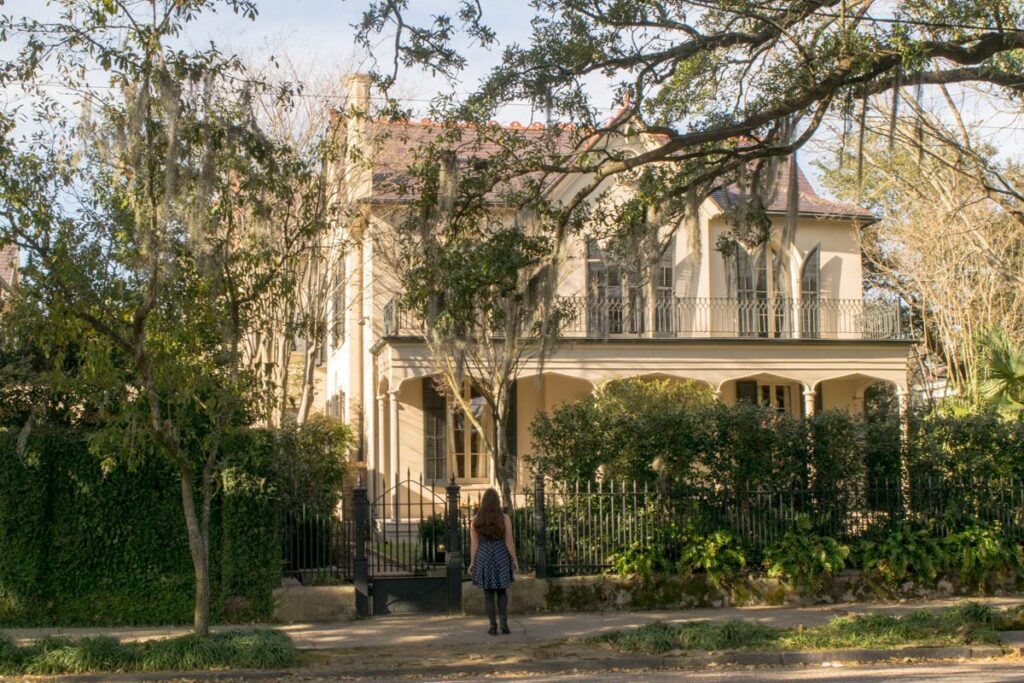 Kate Storm in a polka dot dress looking up at a tan Garden District Mansion during a 3 days in New Orleans itinerary
