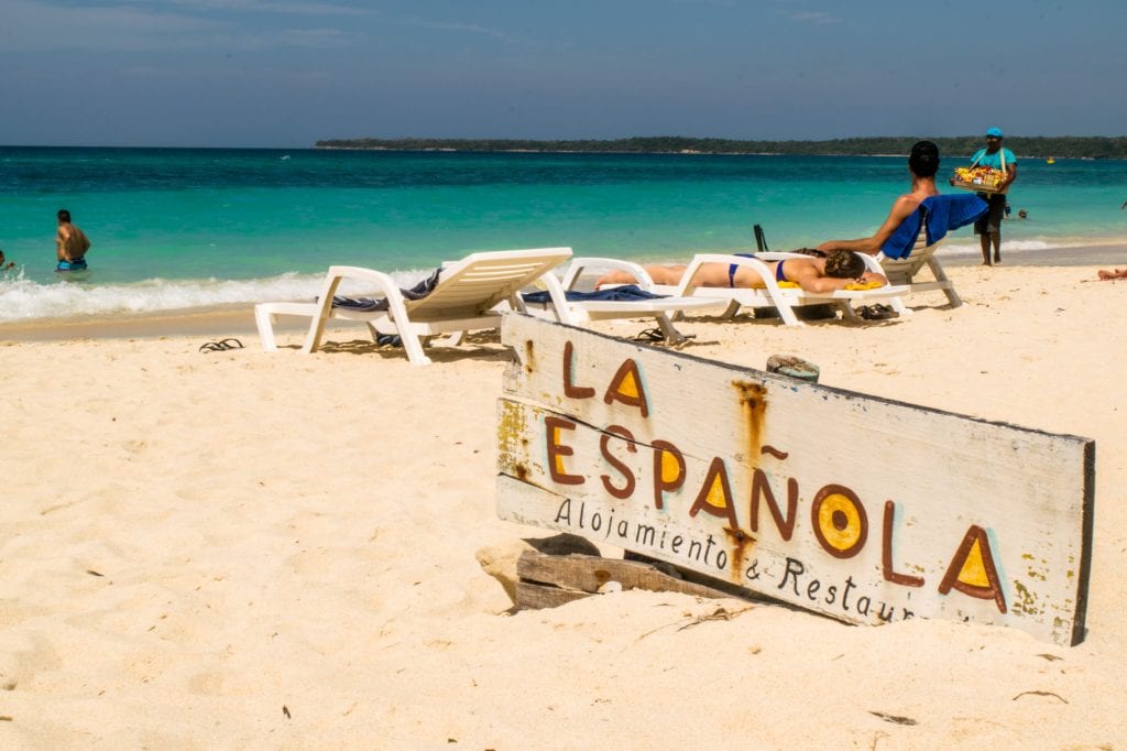 Playa Blanca, Cartagena: La Espanola Cafe sign nestled in the sand with sun chairs in the background