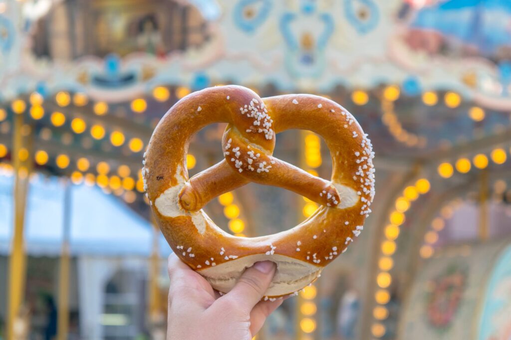 Pretzel being held up to a carousel in during one day in Strasbourg France