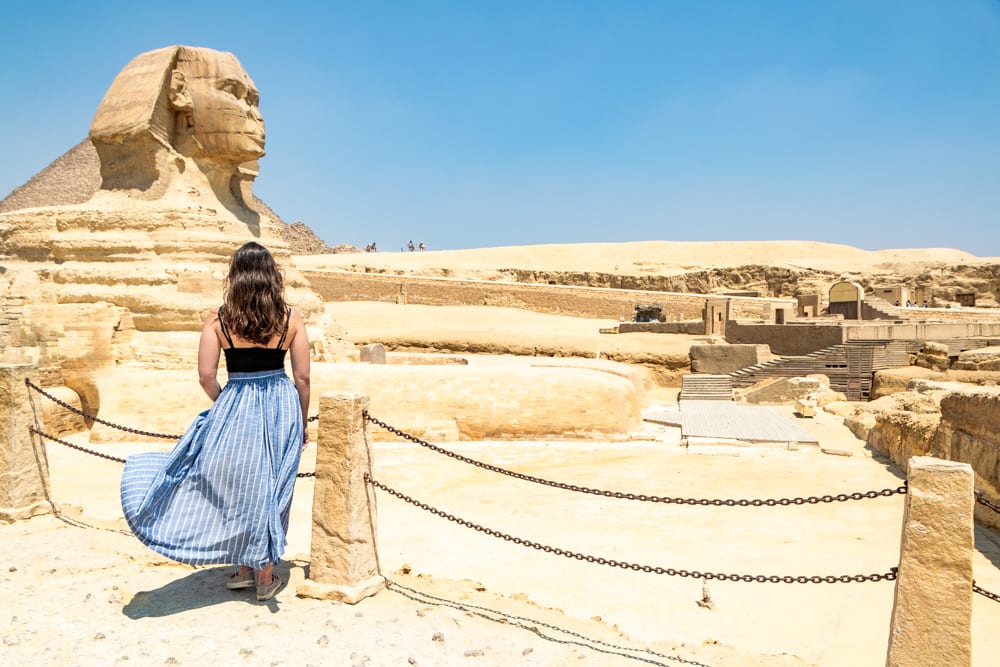 kate storm wearing a blue skirt in front of the great sphinx during a long layover in cairo egypt