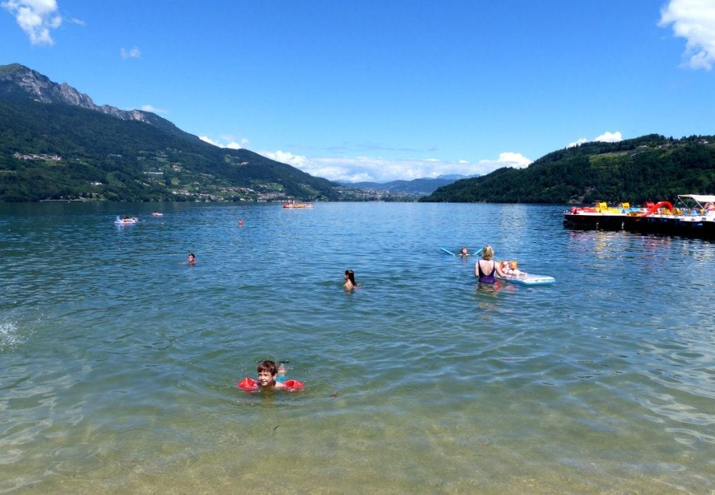 Photo of people swimming near a beach on lake caldonazzo, one of the prettiest italian lakes to visit