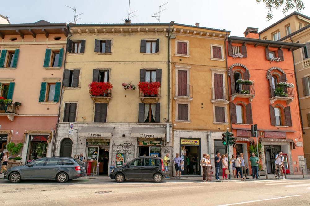 colorful buildings in verona italy with flowers in the window boxes and a couple of cars parked in front