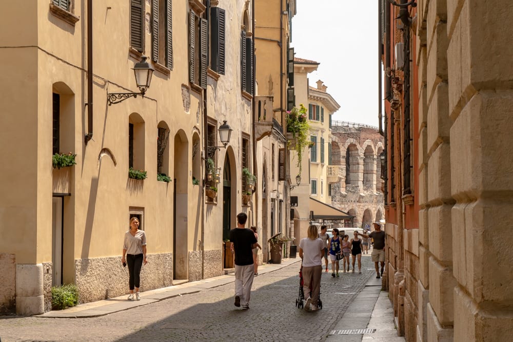 people walking down a shady side street in centro storico, one of the best places to visit verona italy