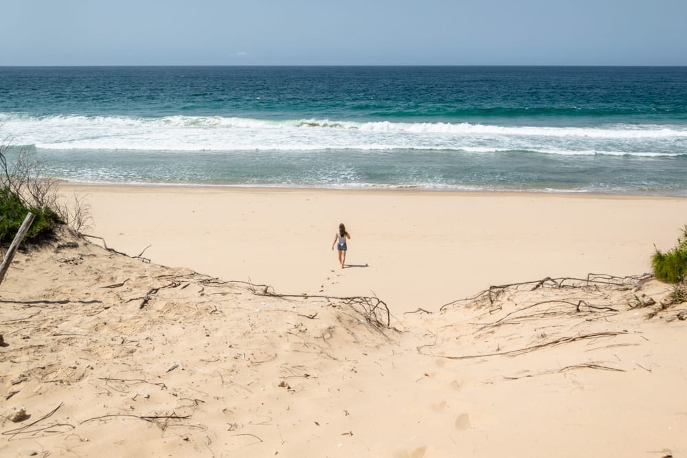 kate storm walking toward water on empty beach in tofo mozambique