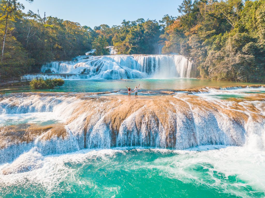 couple standing on agua azul in chiapas, one of the best mexico waterfalls