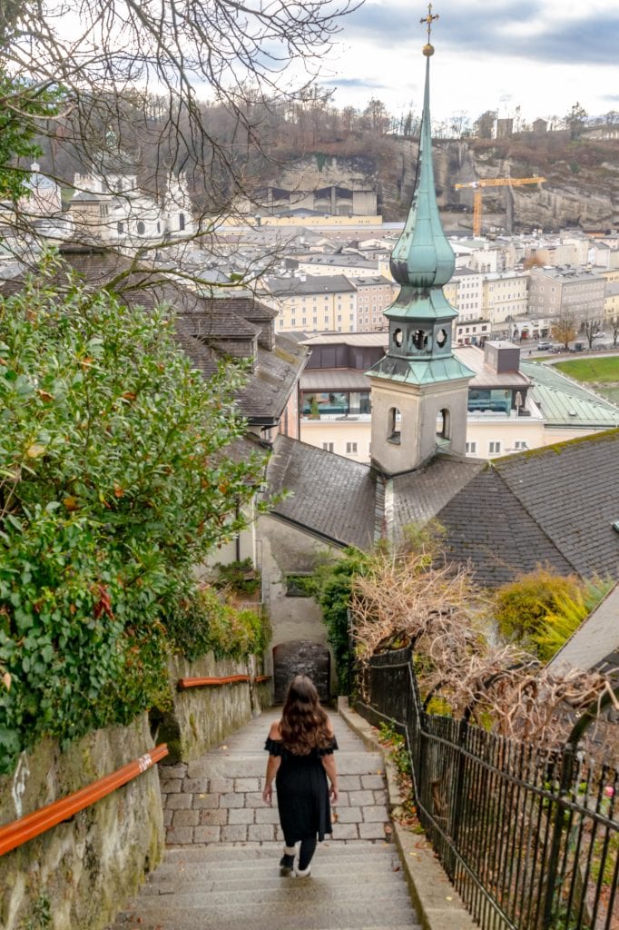 kate storm in a black dress walking down a staircase in salzburg austria