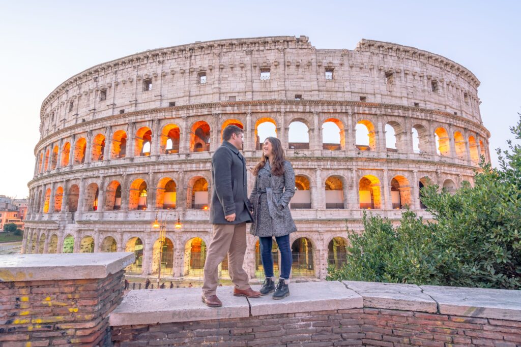 kate storm and jeremy storm wearing winter coats in front of the colosseum in rome italy