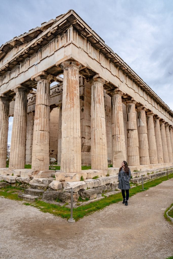 kate storm in a coat standing in front of the ancient agora building when visiting athens on a cloudy day