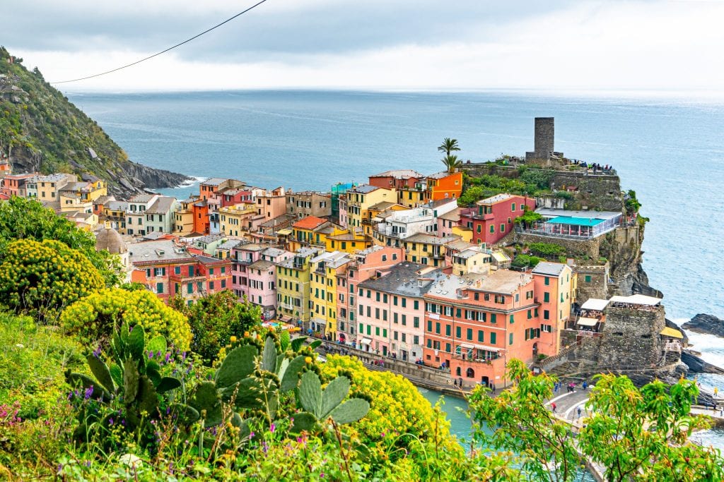 View of Vernazza starting to peek out with greenery in front as you approach the town from Monterosso al Mare--one of the best sections of trail for finding photo spots in Cinque Terre