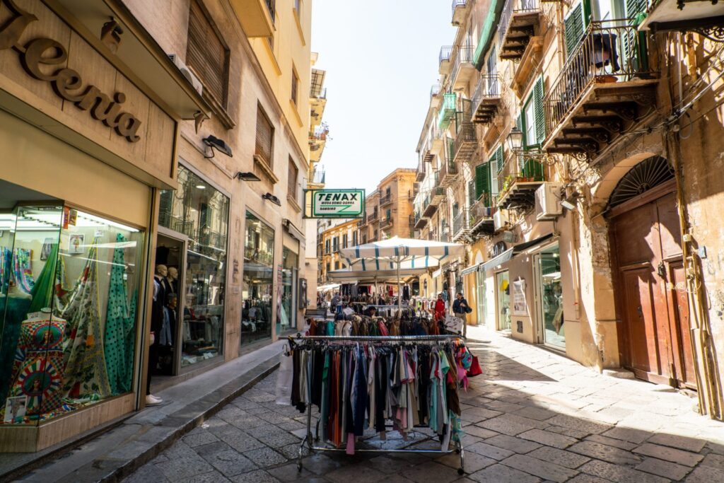 Street with racks of clothes for sale outside, Palermo Sicily