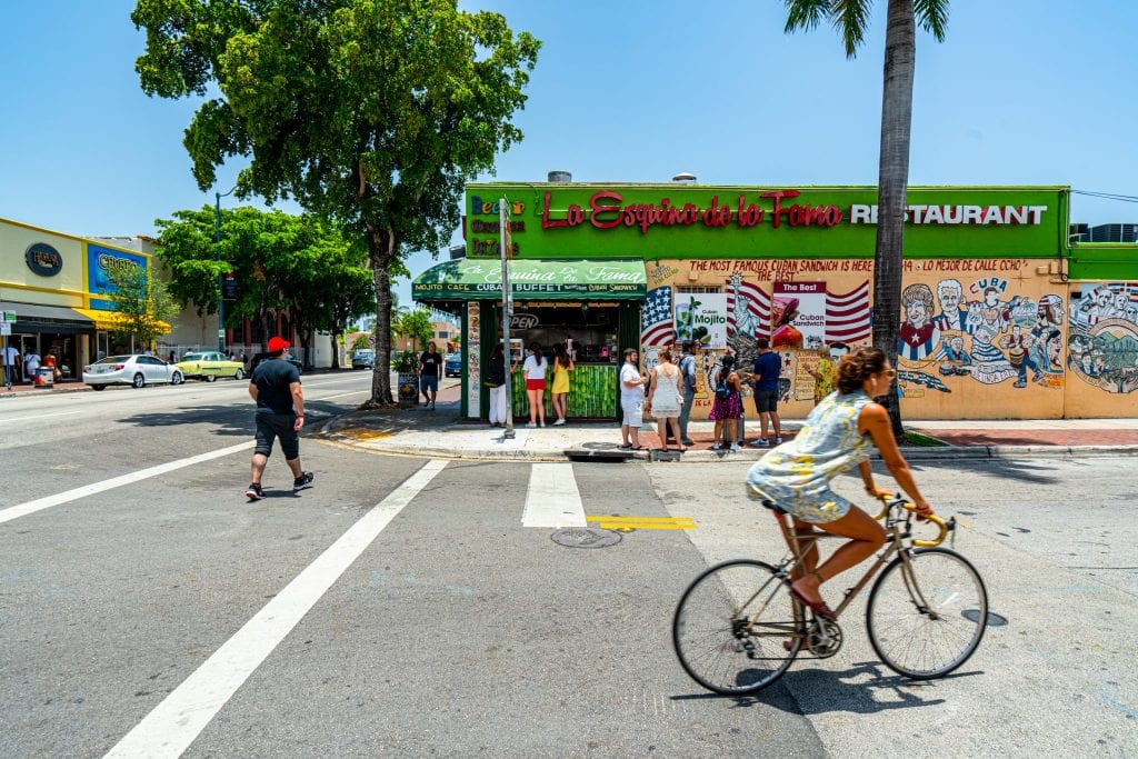 woman riding a bike in front of a green building in little havana miami long weekend