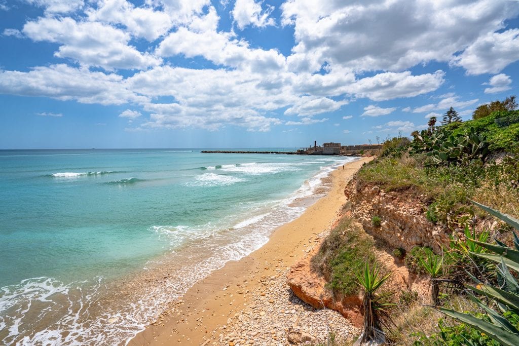 Long stretch of empty beach in Avola Sicily with the clear sea visible on the left, an excellent stop on any Sicily road trip itinerary