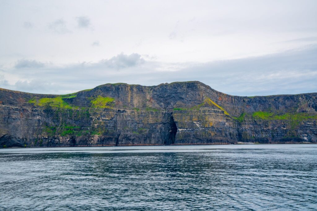 View of sea cave near the Cliffs of Moher used when filming Harry Potter and the Half-Blood Prince, as seen from the water on a cloudy day.