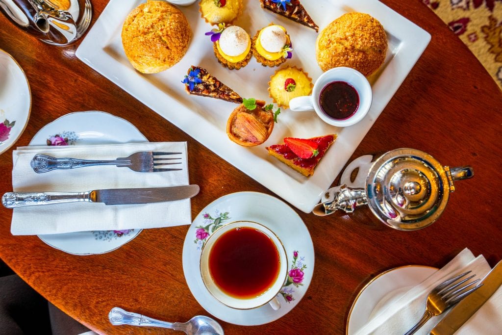 Photo of an afternoon tea in Ireland taken from above, with a collection of sweets, a silver teapot, and a cup of tea