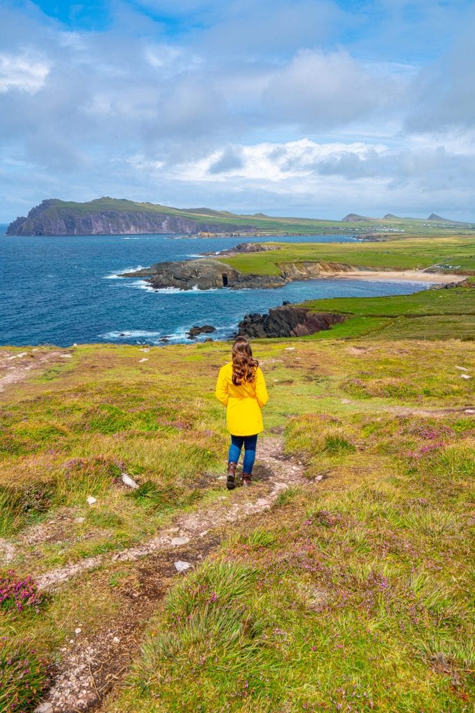 Kate Storm in a yellow raincoat at Dunmore Head Ireland, with the Three Sisters visible in the background