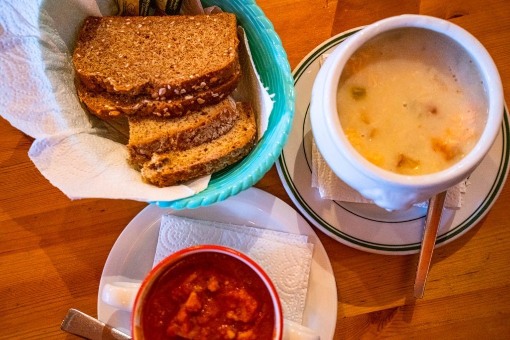 Irish brown bread with two cups of soup next to it, one of the best things to try when deciding what to eat in Ireland
