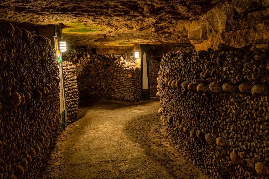 dark and empty path lit by lanterns curving through the catacombs paris france