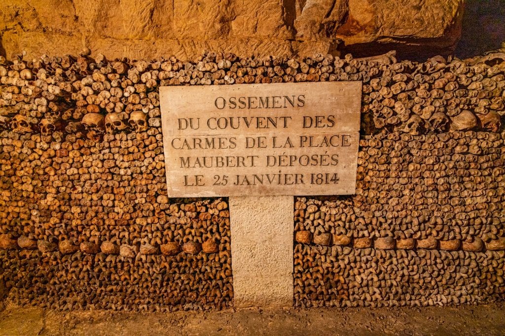 interior of paris catacombs with a sign in front of the bones