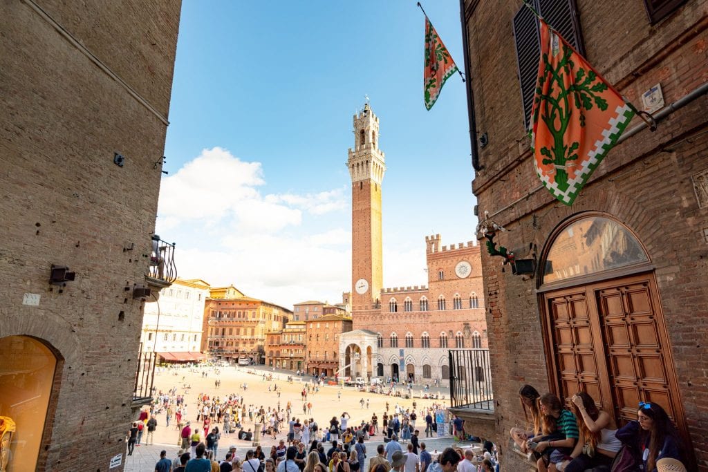 view of piazza del campo from a small street just off the piazza, one of the best places to visit in siena day trip from florence