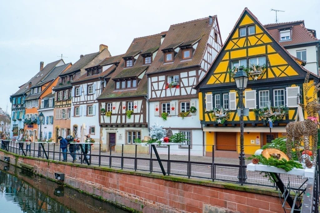 Row of houses in La Petite Venise with a yellow house the most prominent. Located in Colmar France