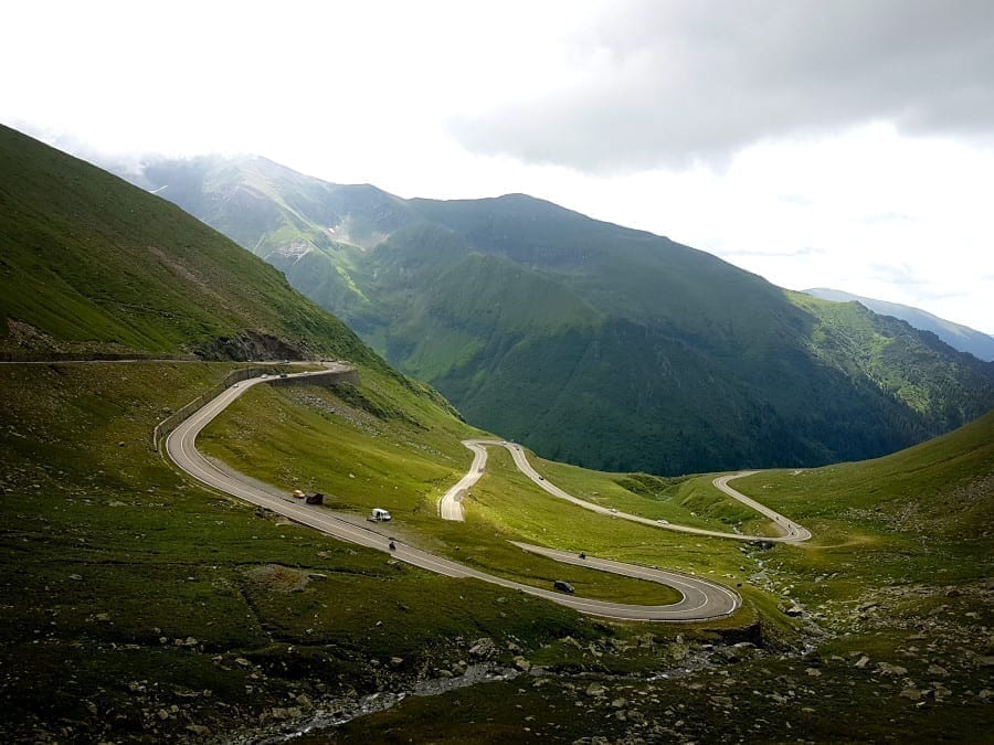 TransfÄgÄrÄČan road winding through the mountains of Romania on a cloudy day--definitely not the easiest road trip in Europe as far as driving goes!