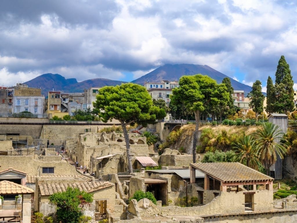 View of ruins of Herculaneum from above with Mount Vesuvius in the background. Herculaneum is one of the easiest Sorrento day trips to take independently.