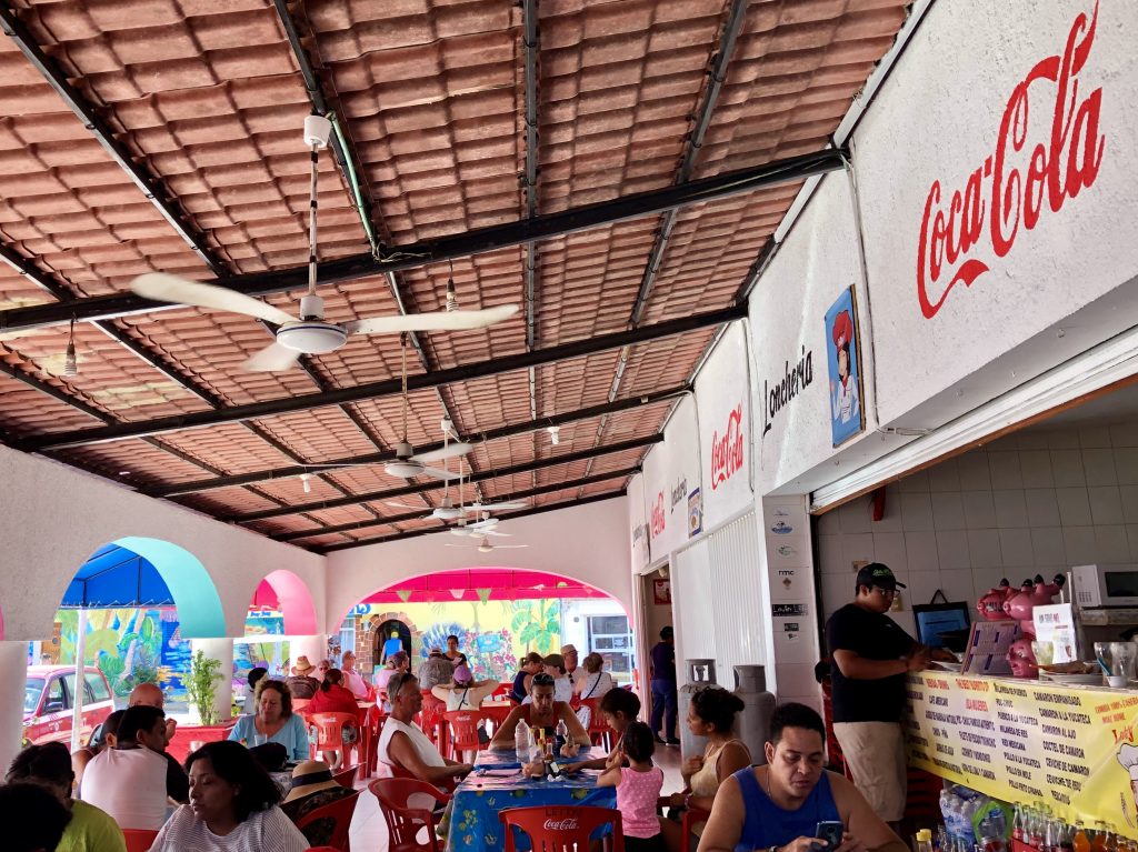 people eating breakfast under ceiling fans at mercado municipal, one of the best places to visit in isla mujeres mexico
