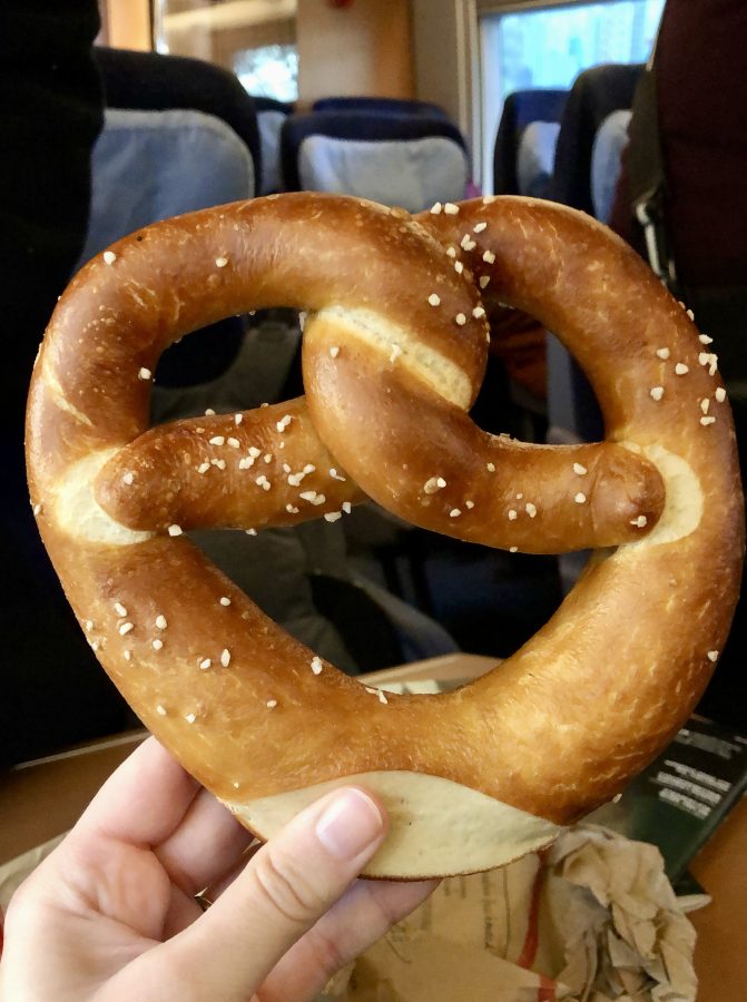 hand holding up a pretzel on a train in germany