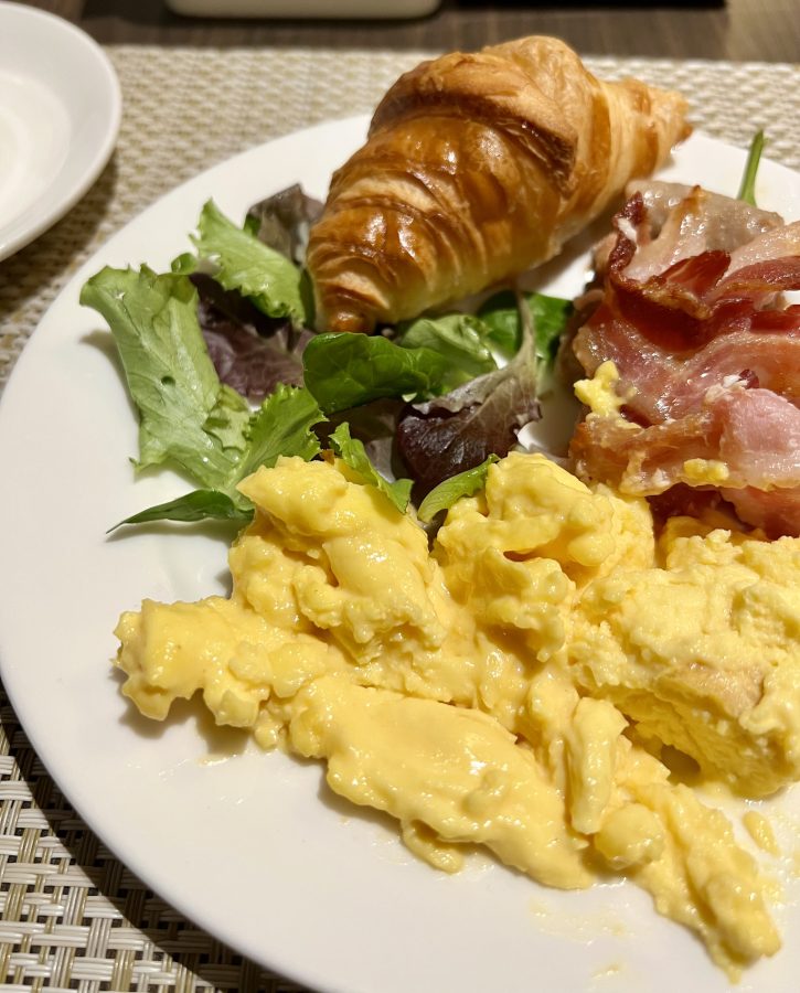 plate of scrambled eggs cured meat salad and cornetto from an italian breakfast buffet in milan