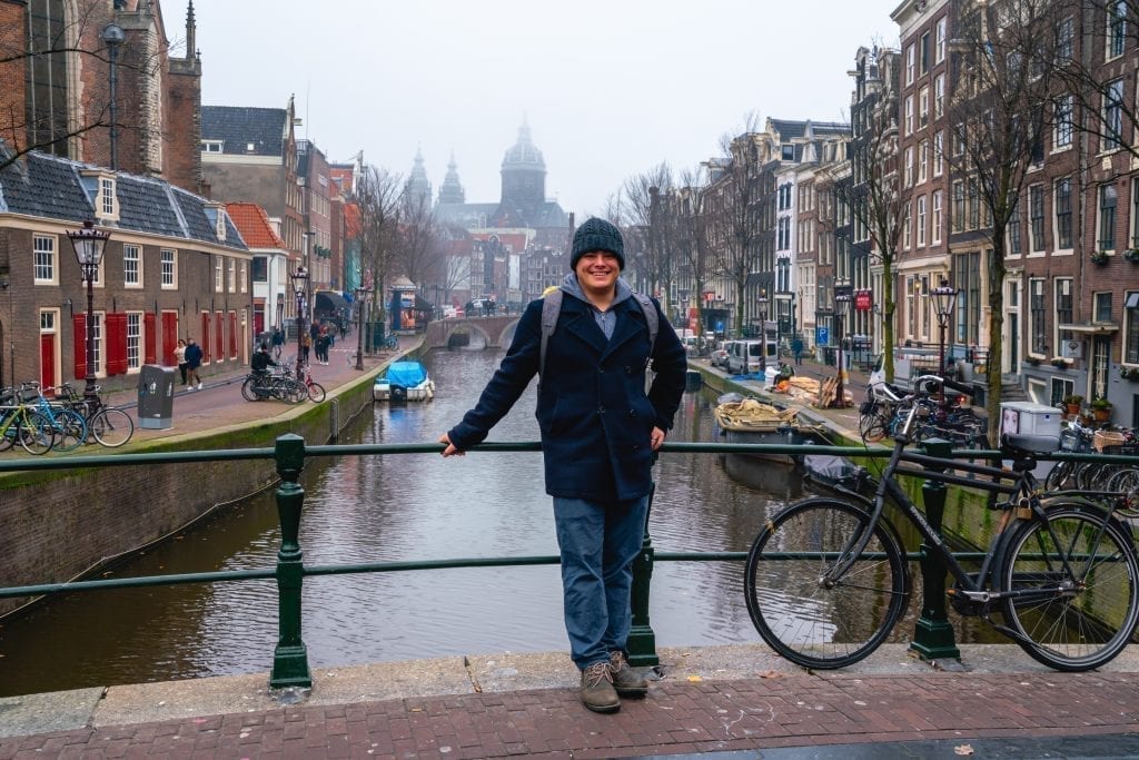 Jeremy Storm leaning against a bridge during one day in Amsterdam on a cloudy evening
