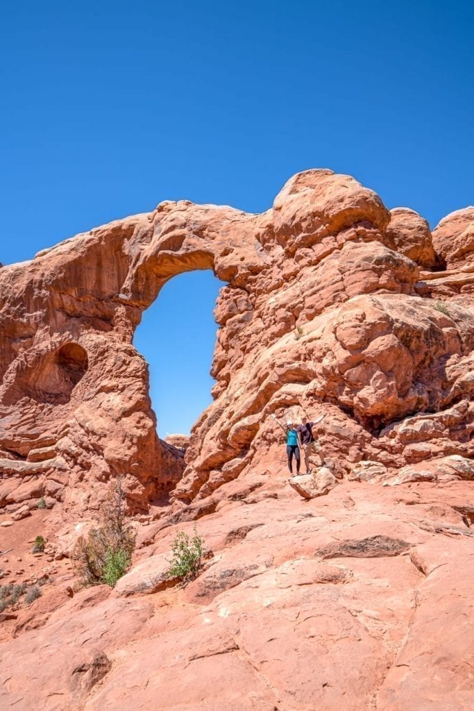 Kate Storm and Jeremy Storm standing in front of Turret Arch when hiking in Arches National Park